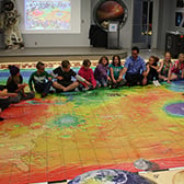 CHILDREN SITTING ON MAP OF MARS