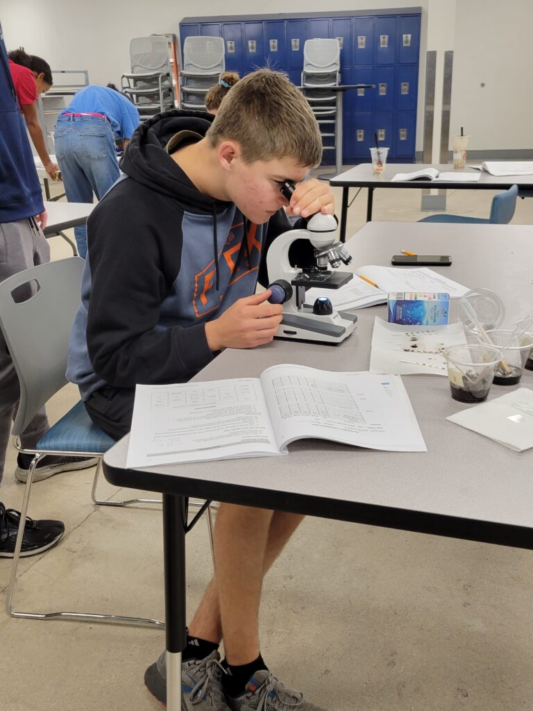 jsep student looks through microscope